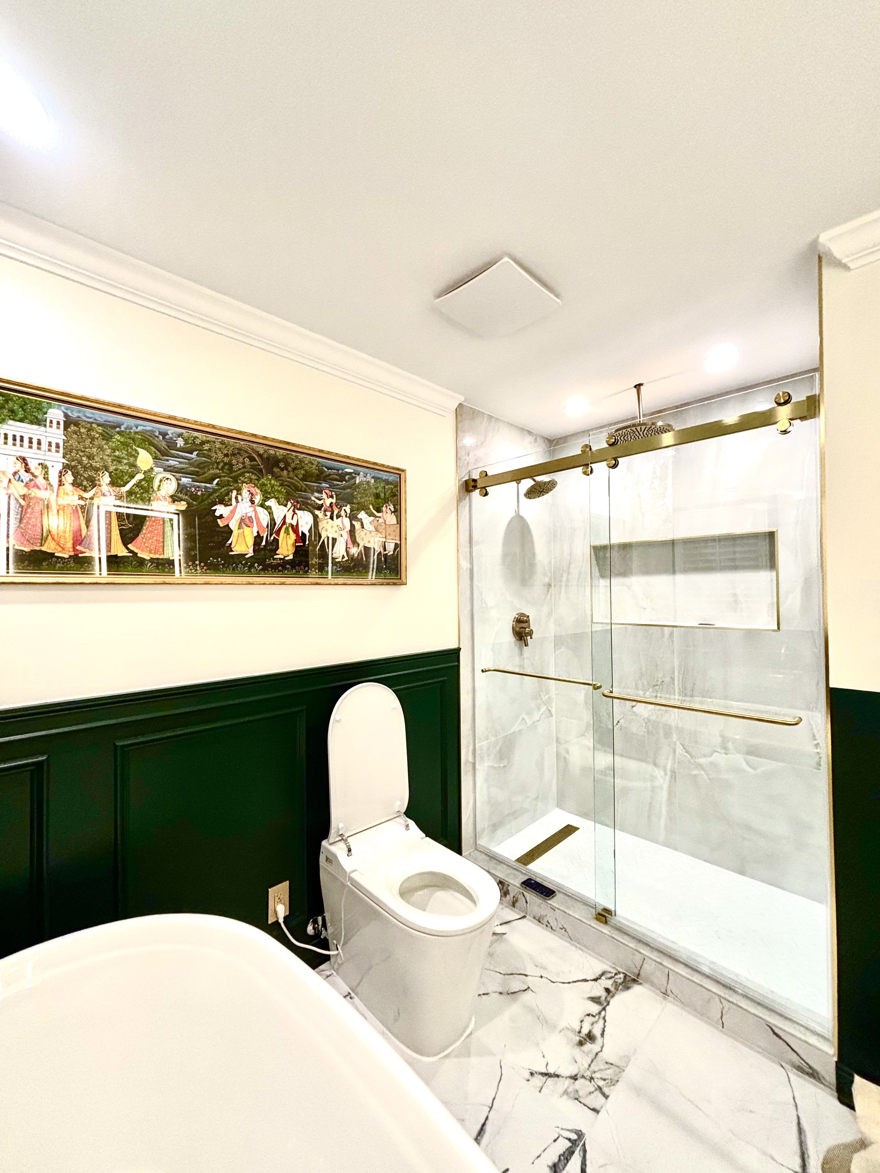 Smart toilet beside a glass walk-in shower with a gold sliding door and rain shower head