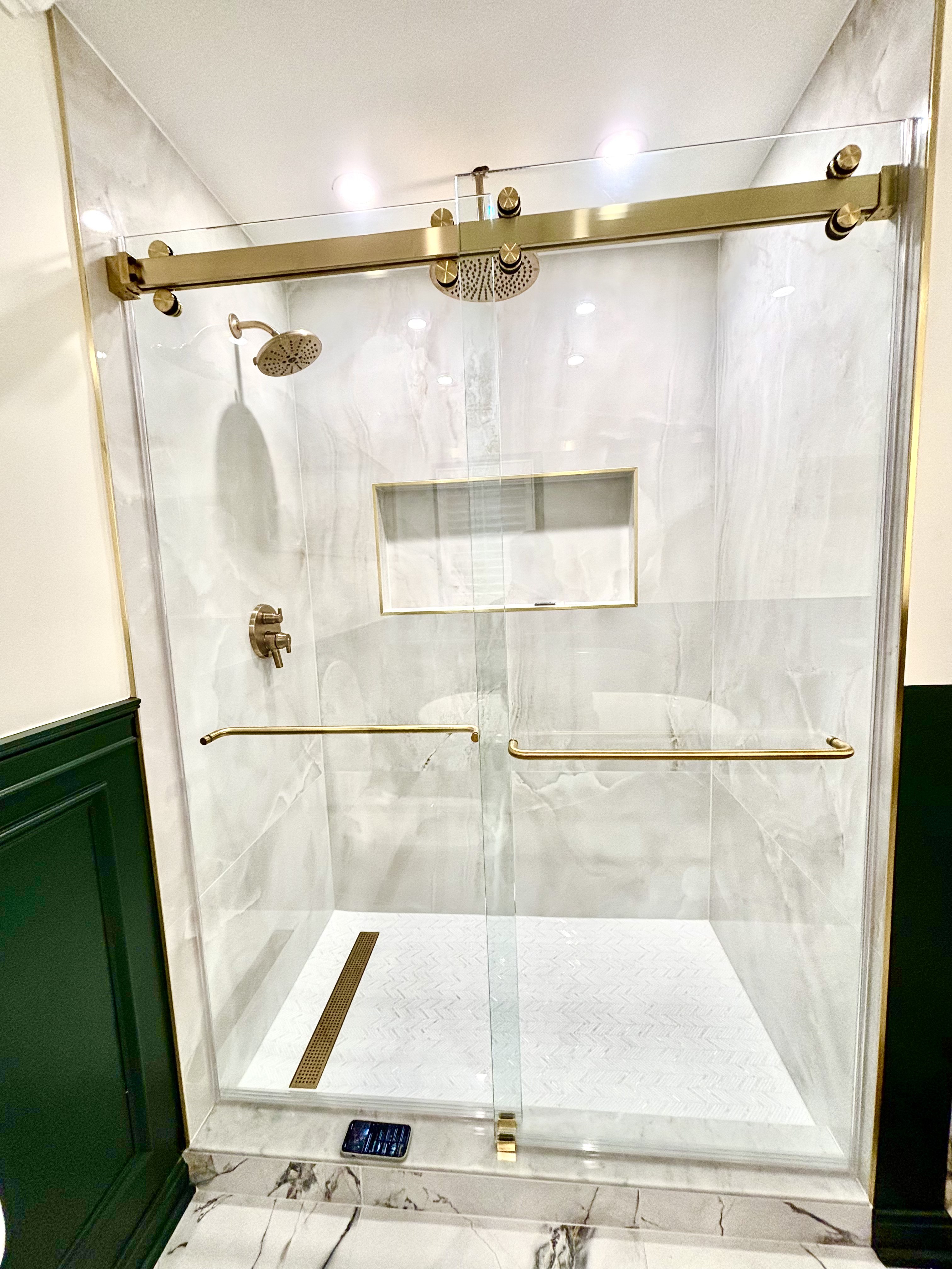 Walk-in shower with a recessed wall niche, gold linear drain and herringbone shower floor