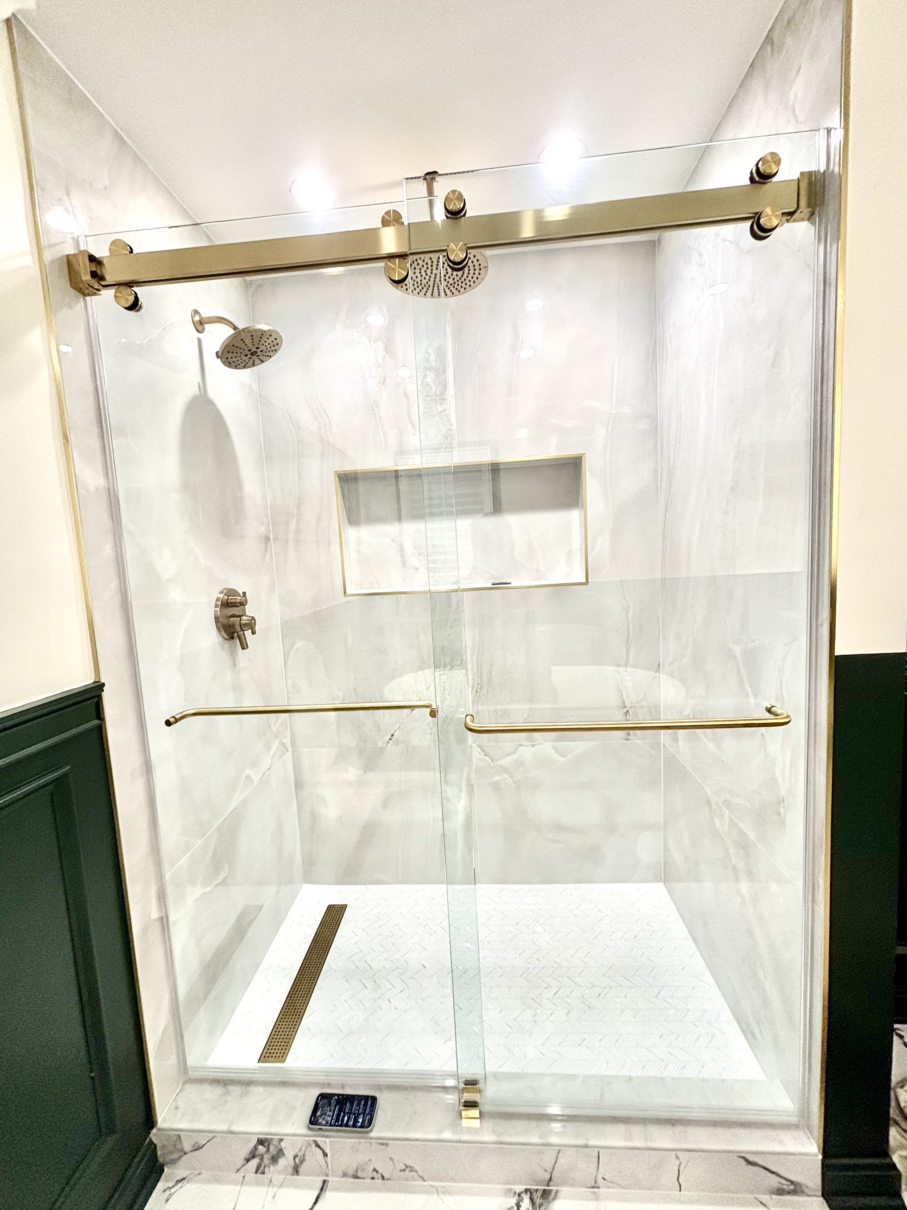 Front view of the walk-in shower with a ceiling-mounted rain head, a wall shower head and gold fixtures